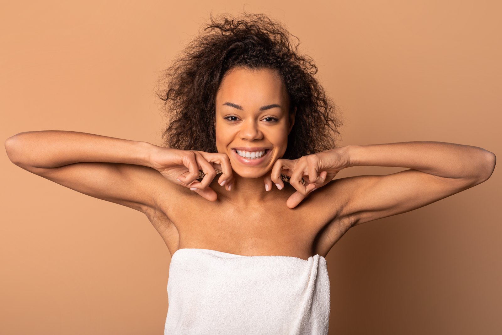 Smiling woman with natural curly hair showing underarms after hair removal
